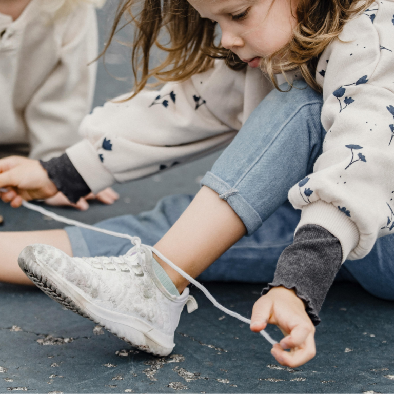 Enfant apprenant à faire ses lacets avec une approche orientée tâche